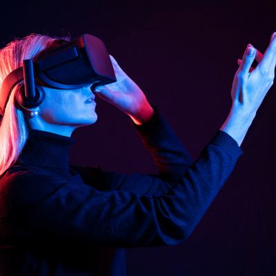 Femme portant un casque de réalité virtuelle, la main levée vers ce qu'elle regarde